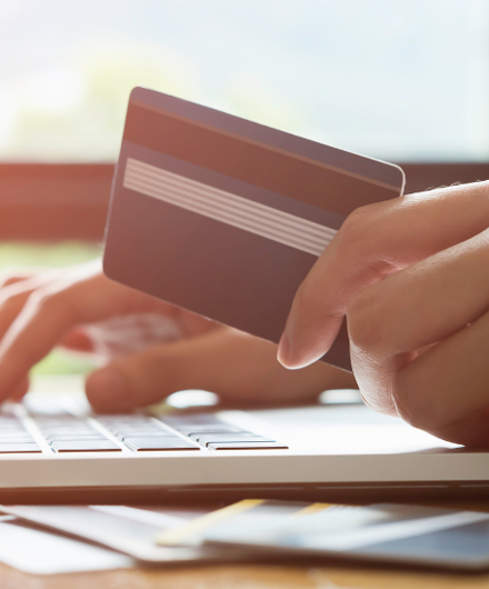 Hand Holding A Credit Card And Typing At A Laptop 