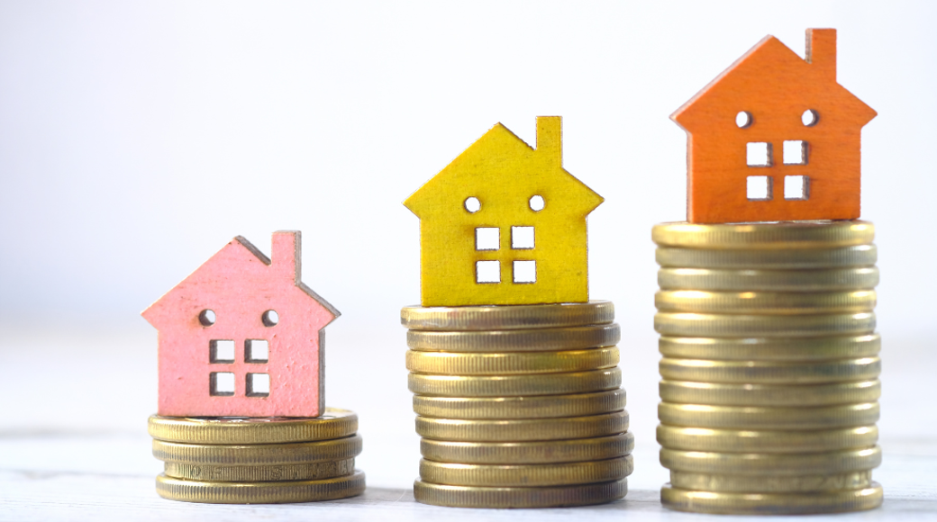 Pink, Yellow And Orange House Figure On The Top Of A Pile Of Coins Increasing Height Of Pile Each Time