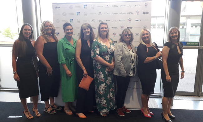 Female Tenants And Staff Members Standing In A Row At An Award Ceremony 