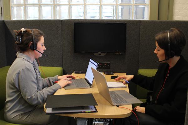 Two Members Of Saffron Sat At A Desk