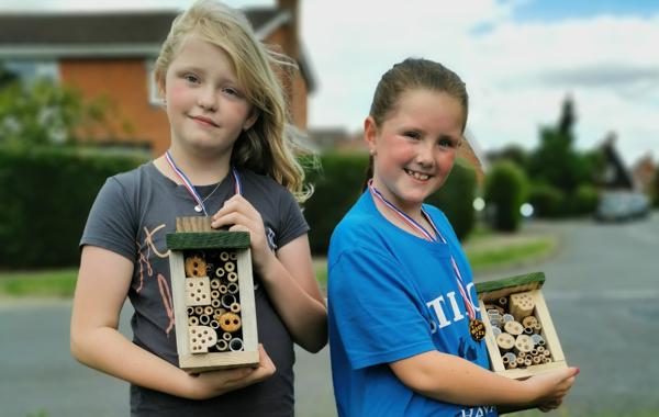 Two Children Holding Bug Hotels