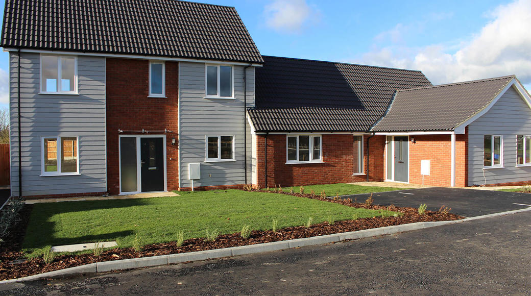 Row Of Homes With Red Brick And Light Grey Wooden Cladding And Green Grass