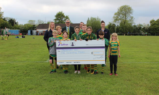 Group Of Children And Saffron Staff Standing Behind Giant Cheque