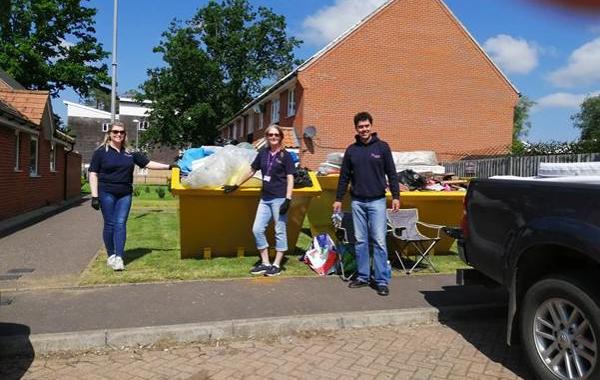 3 Saffron Staff Members Standing In Front Of A Yellow Skip On A Sunny Day