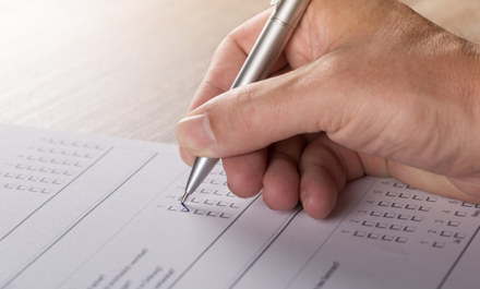 Hand Holding Pen Filling Out Paper Application Form