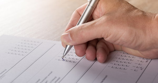 Hand Holding Pen Filling Out Paper Application Form