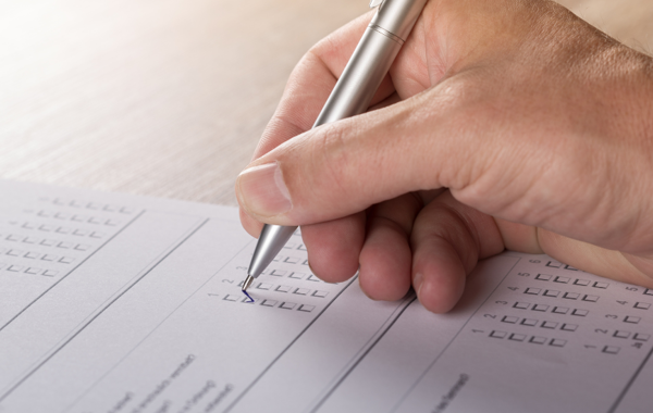 Hand Holding Pen Filling Out Paper Application Form