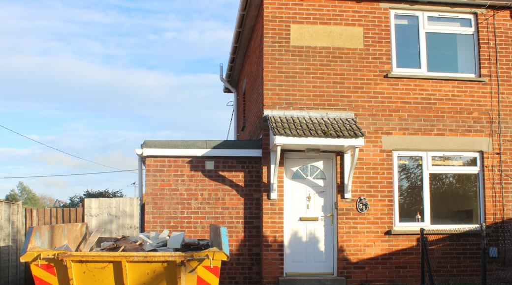 House With Yellow Skip Outside